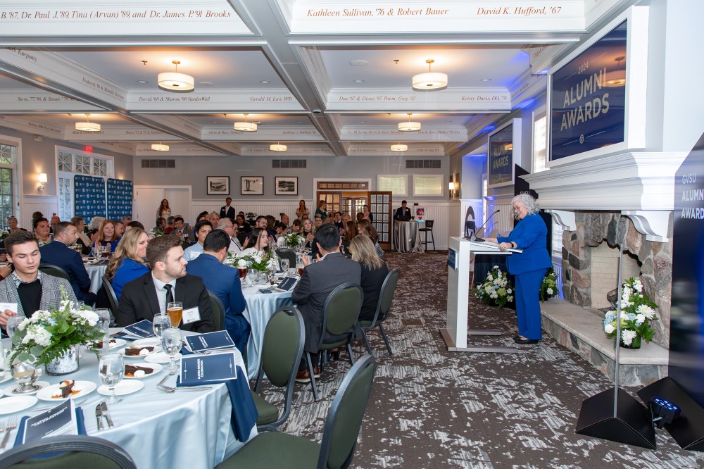 Susan Proctor smiles with she is speaking at podium